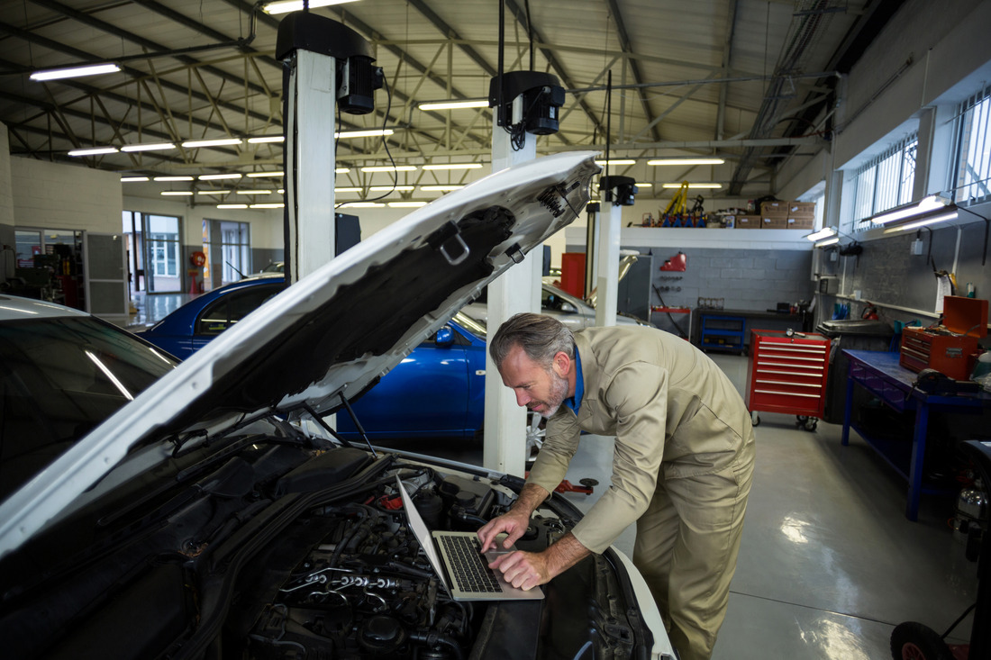 mechanic-using-laptop-while-servicing-car-engine (1)